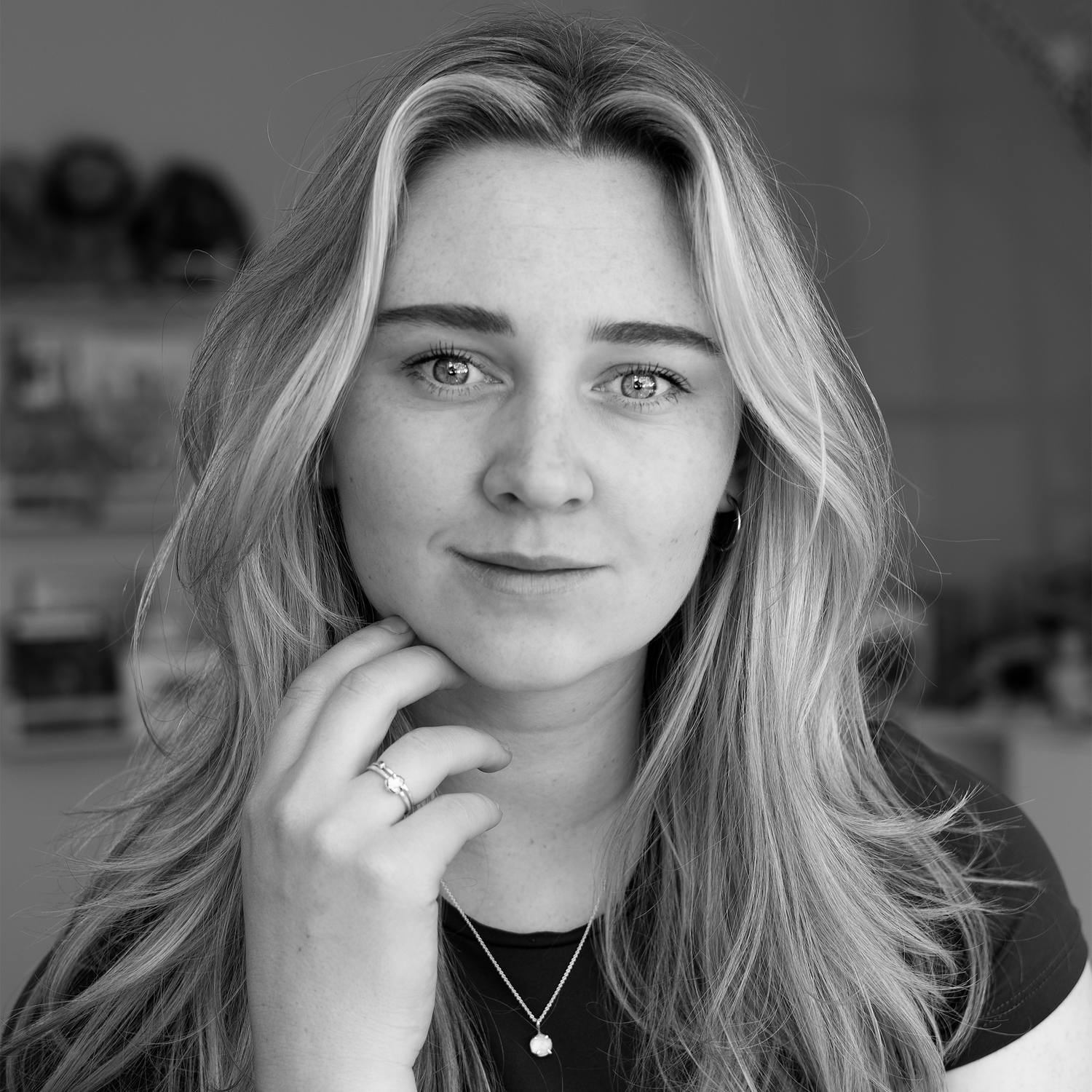 Portrait of Sara, founder of ISH Jewellery, wearing a raw-cut gemstone necklace and ring, looking confidently at the camera.